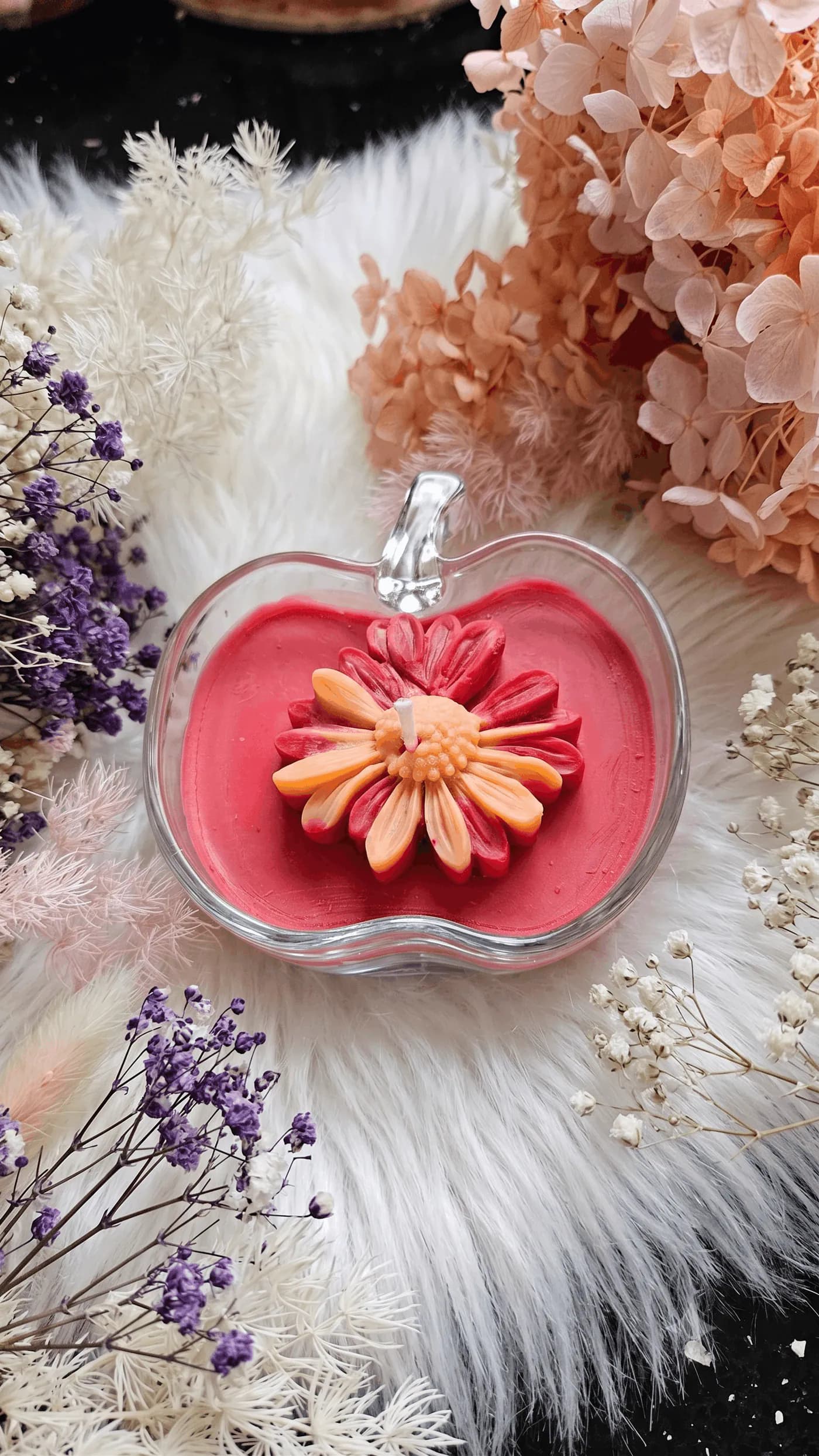 Red flower candle in a clear apple-shaped vessel