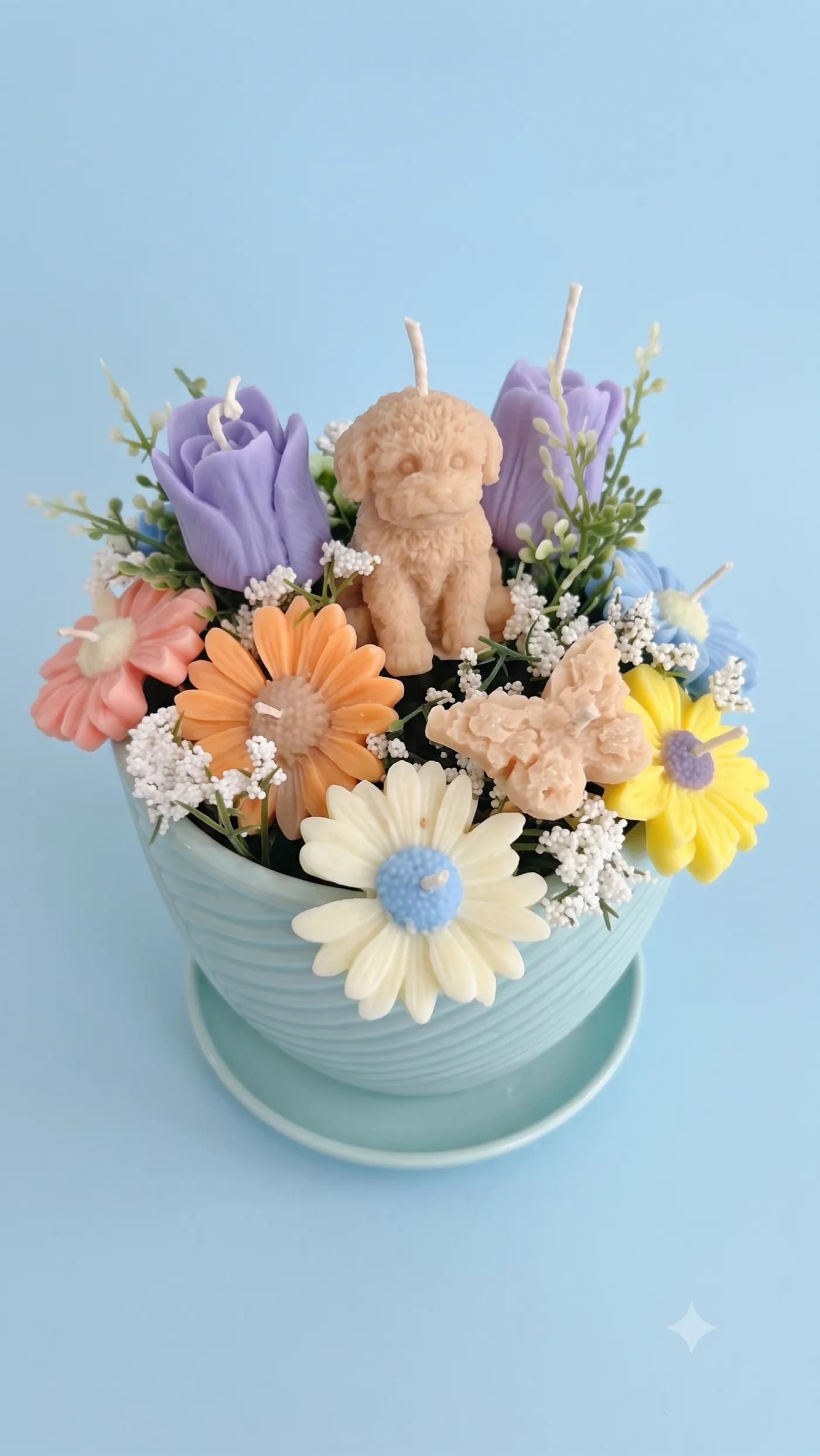 Pastel floral candle arrangement with a teddy bear centre