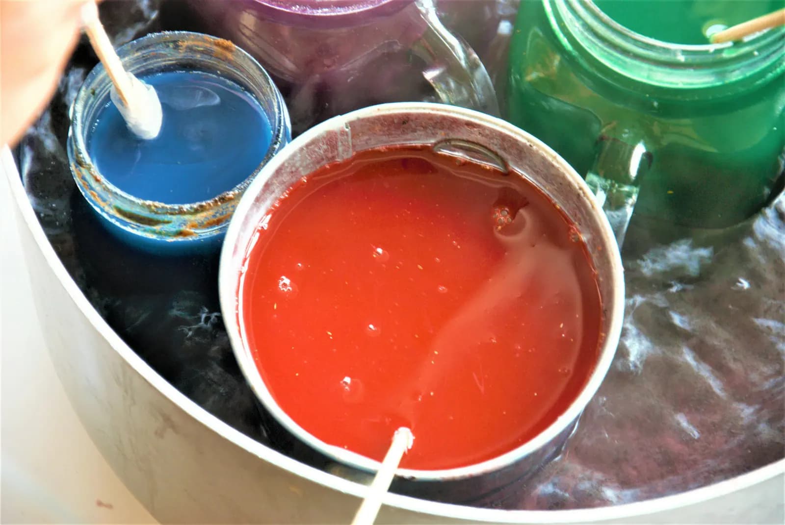 Small vessels of coloured wax during the candle-making process