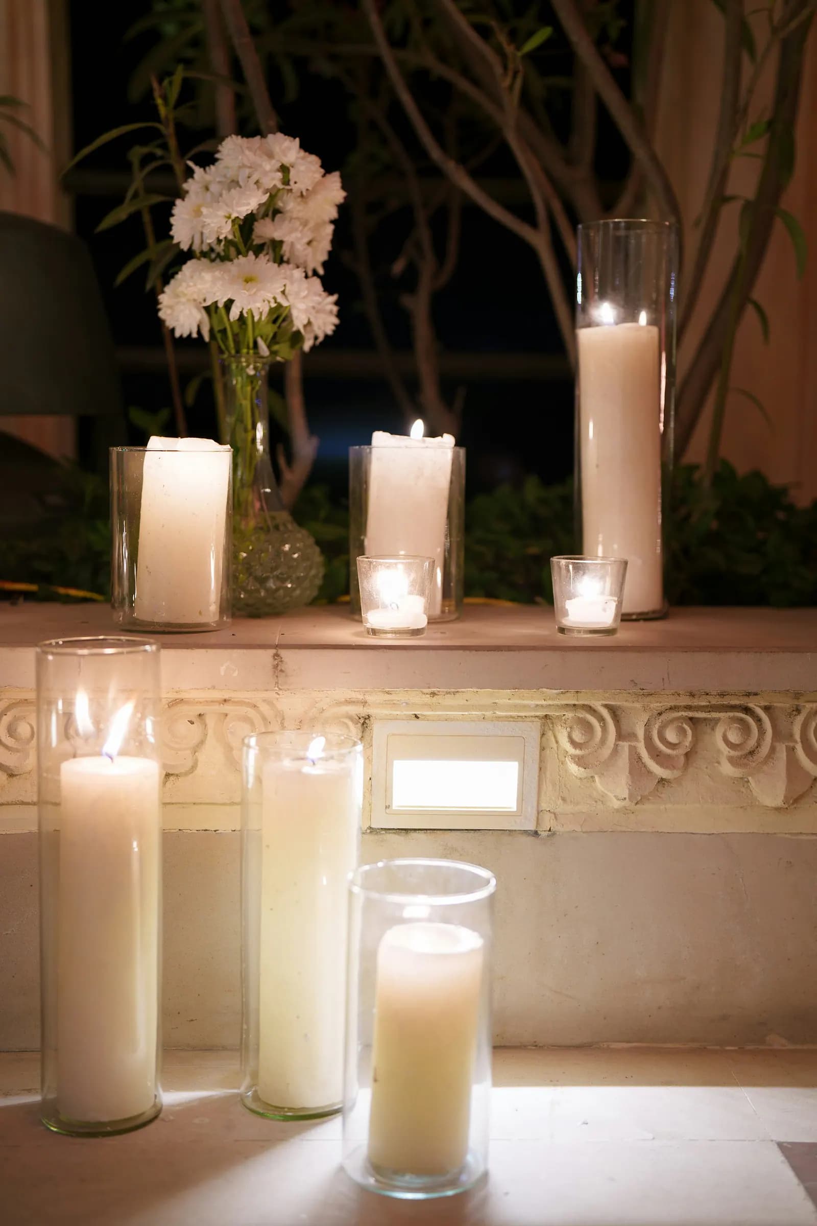 White pillar candles and flowers glowing in an evening setting